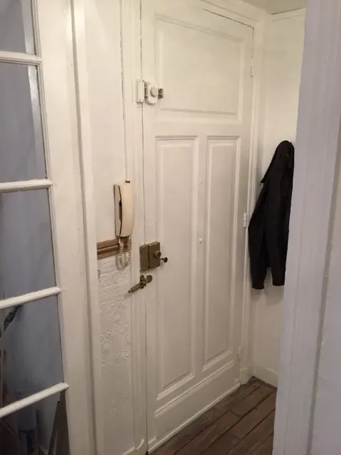Porte d'appartement blanche équipée d'une serrure en applique en laiton