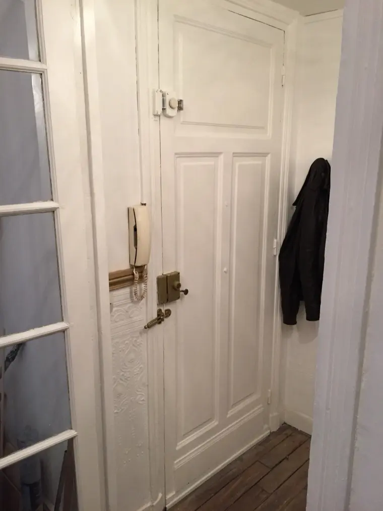Porte d'appartement blanche équipée d'une serrure en applique en laiton