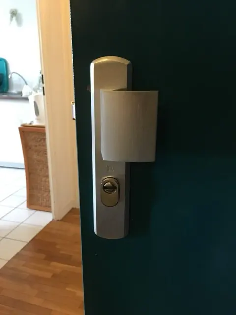 Plaque de protection en inox et rosace anti-perçage montées sur une porte d'entrée