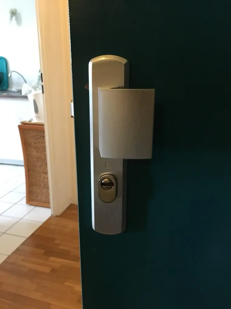 Plaque de protection en inox et rosace anti-perçage montées sur une porte d'entrée