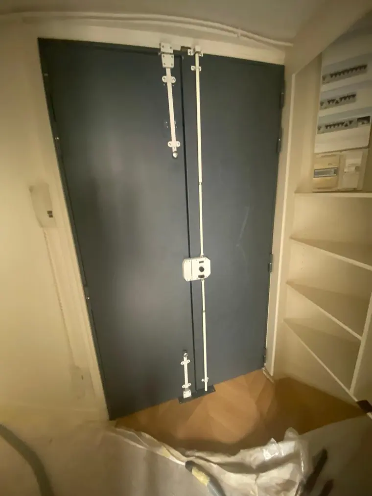 Pose d'une serrure multipoints sur une double porte, sol protégé pendant l'intervention