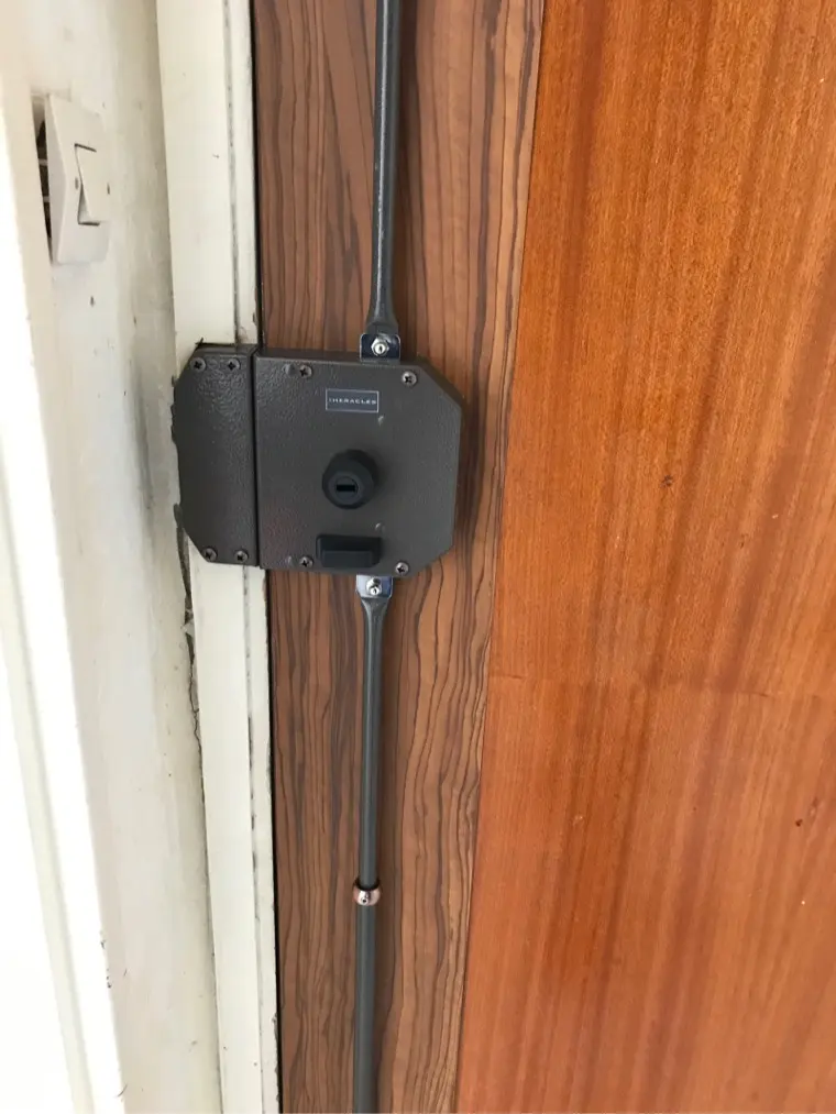Serrure Héraclès en applique montée sur une porte en bois verni