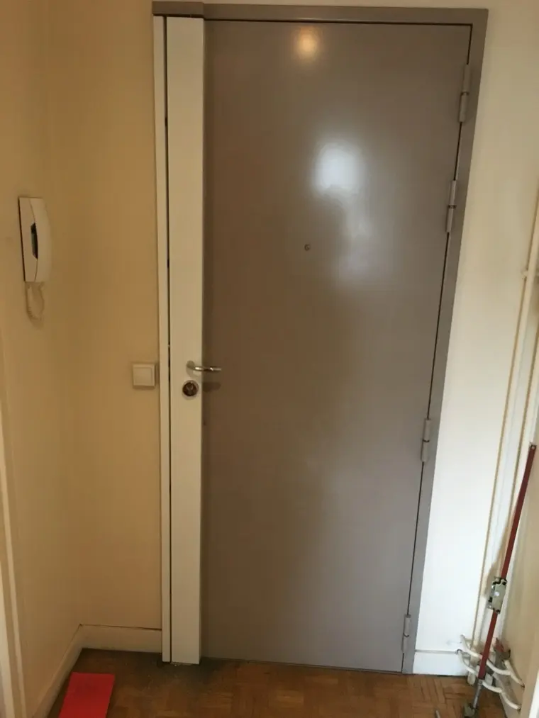 Porte blindée gris taupe avec carénage blanc couvrant la serrure