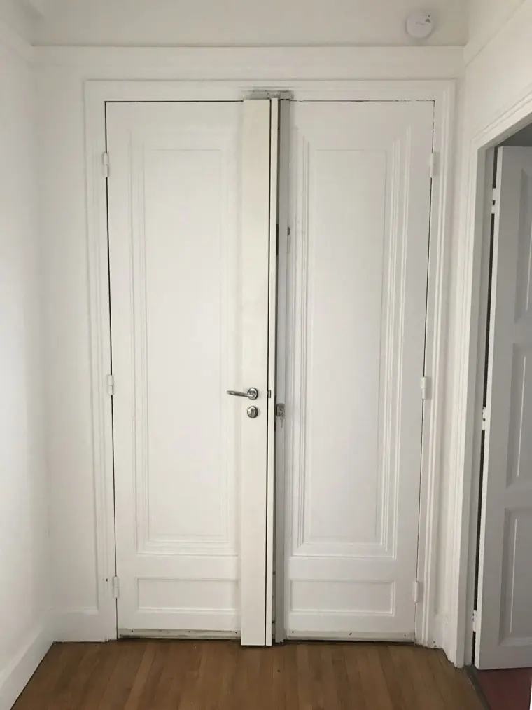Double porte blanche renforcée, paumelles et serrure centrale visibles