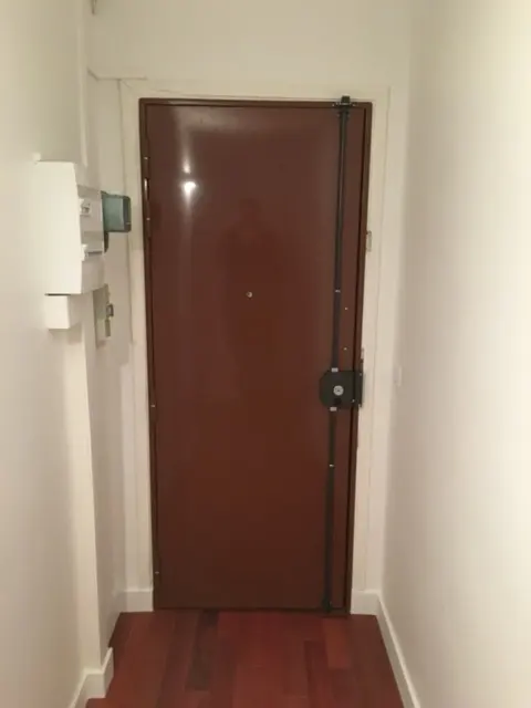 Porte blindée brun foncé équipée d'une serrure en applique à tringle verticale